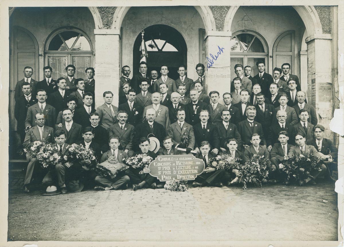 Chorale La Cécilienne posant devant la mairie de Bondues (supposé) après les prix obtenus au grand concours de musique de Béthune le 12 août 1928. Archives municipales de Bondues - 7BON_S20/53